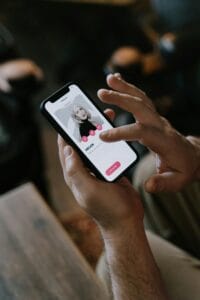 Aplicativos de namoro adotam inteligência artificial para encontrar amor 3 Close-up of hands using a dating app on a smartphone indoors. Modern technology and online dating.