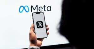 Meta Lança Anúncios na Plataforma Threads e Revoluciona Publicidade 6 Hands holding smartphone with Meta Threads logo on screen, Meta branding in background.